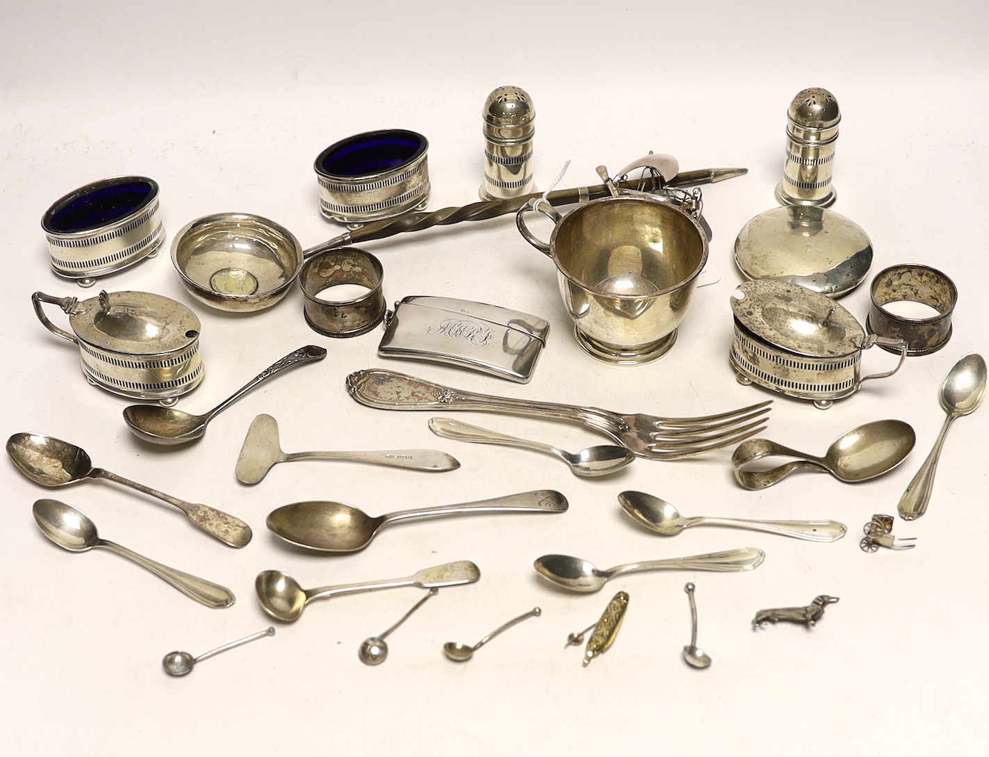 A 1930's silver single handled cup, a four piece silver condiment set, Edwardian silver card case, pair of silver pepperettes, napkin rings, sundry small flatware including sterling etc.